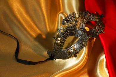 Photo of Beautiful carnival mask on silk fabric, closeup