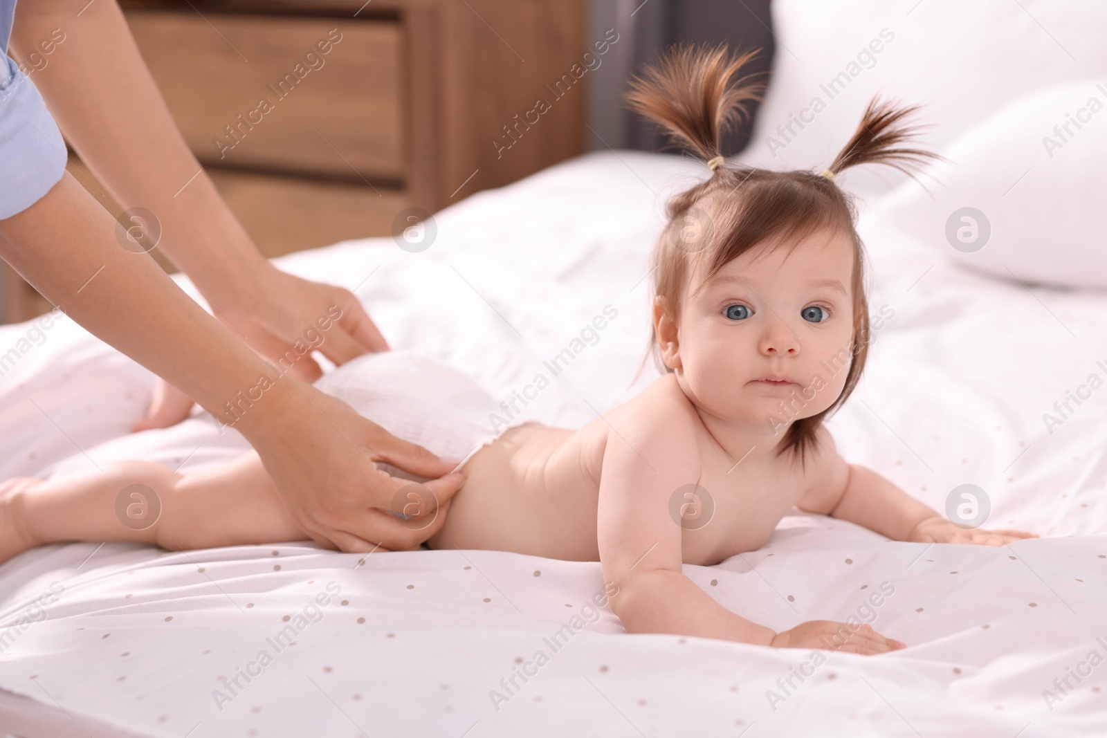 Photo of Mother changing her baby's diaper on bed, closeup