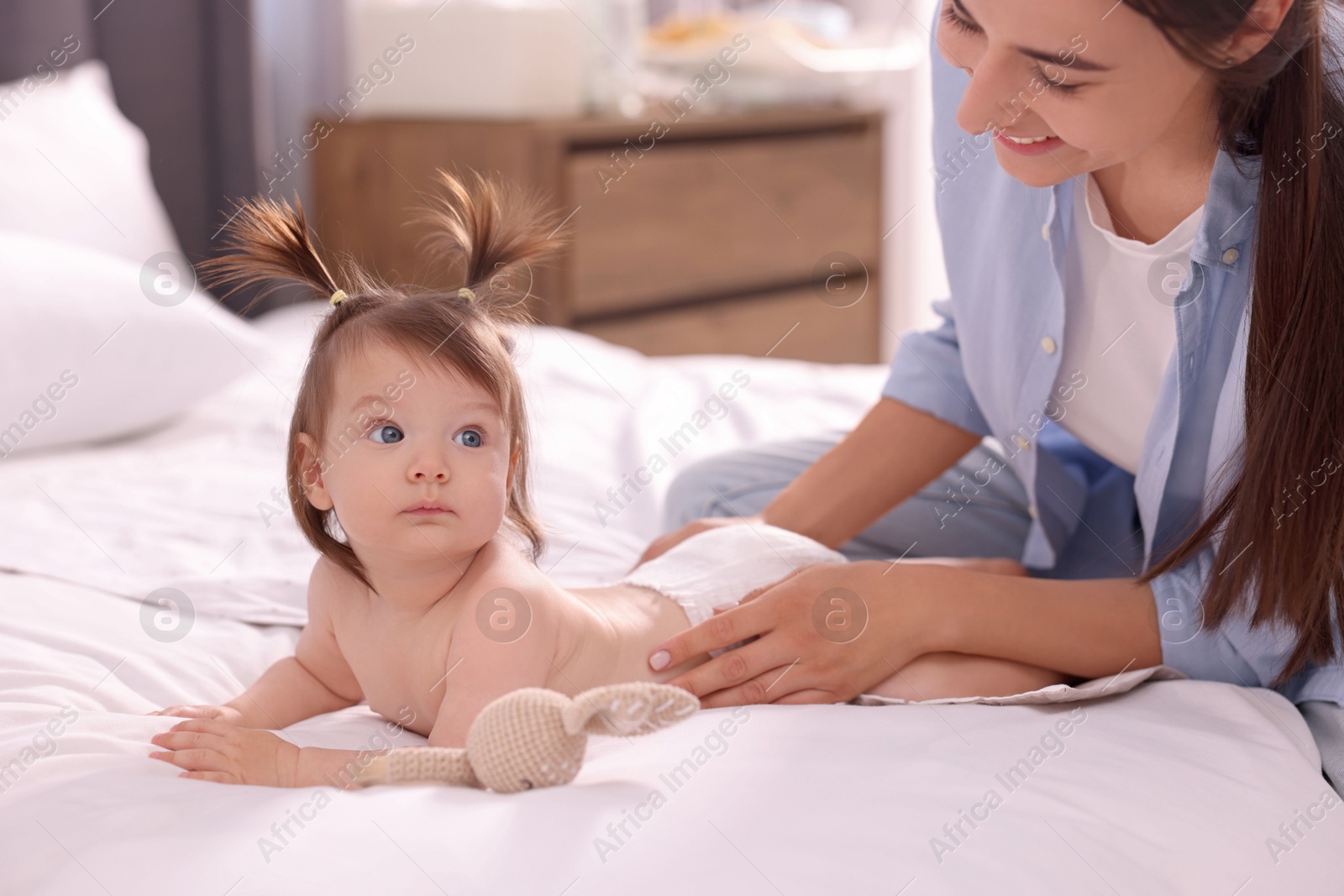 Photo of Mother changing her baby's diaper on bed