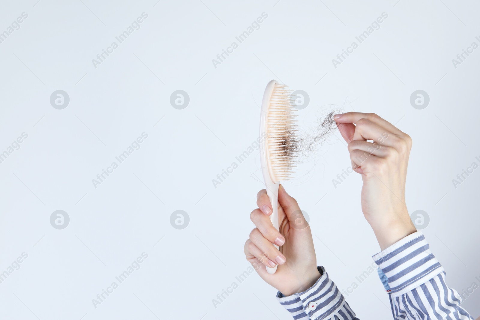 Photo of Woman taking lost hair from brush on light grey background, closeup. Space for text