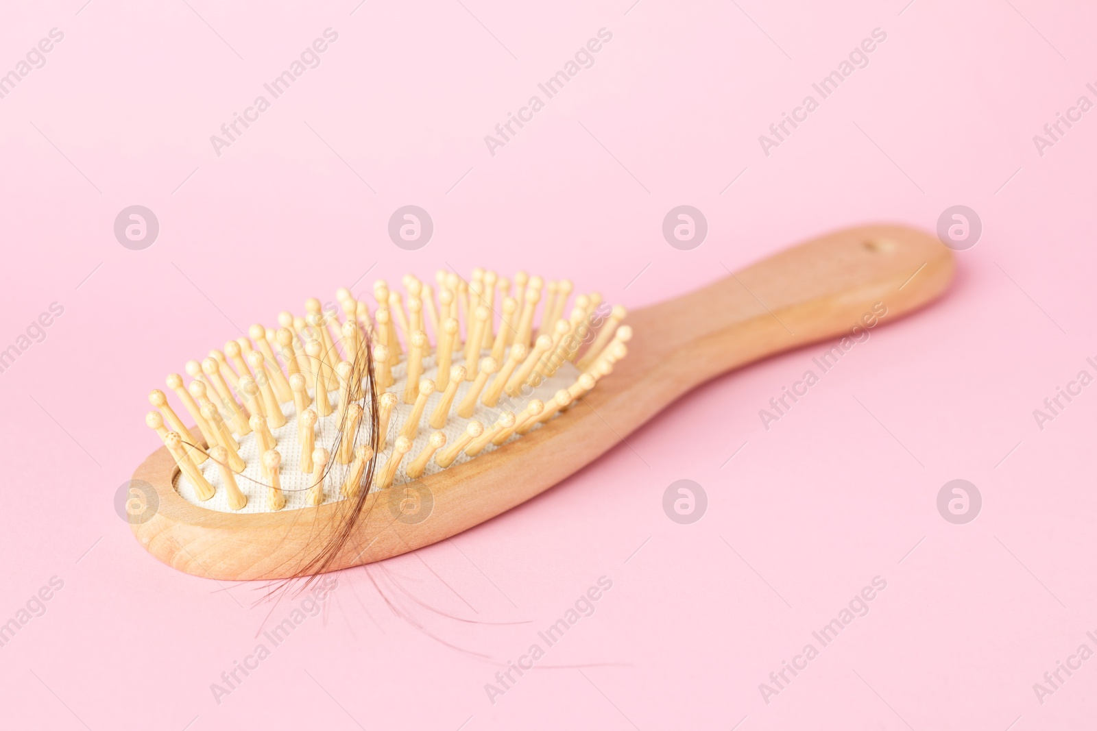 Photo of One brush with lost hair on pink background, closeup