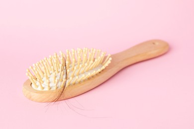 Photo of One brush with lost hair on pink background, closeup