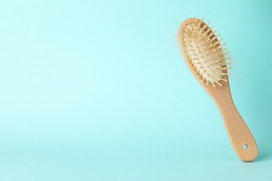 Photo of One brush with lost hair on light blue background, closeup. Space for text