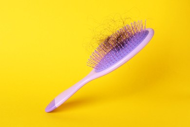 One brush with lost hair on yellow background, closeup