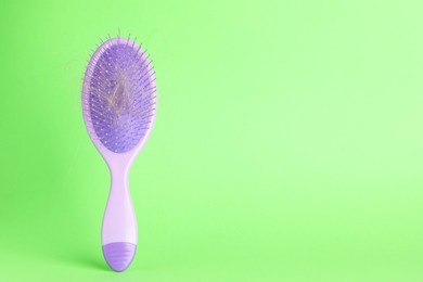 Photo of One brush with lost hair on green background, closeup. Space for text