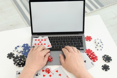 Photo of Man playing poker on laptop at white table, closeup. Online game