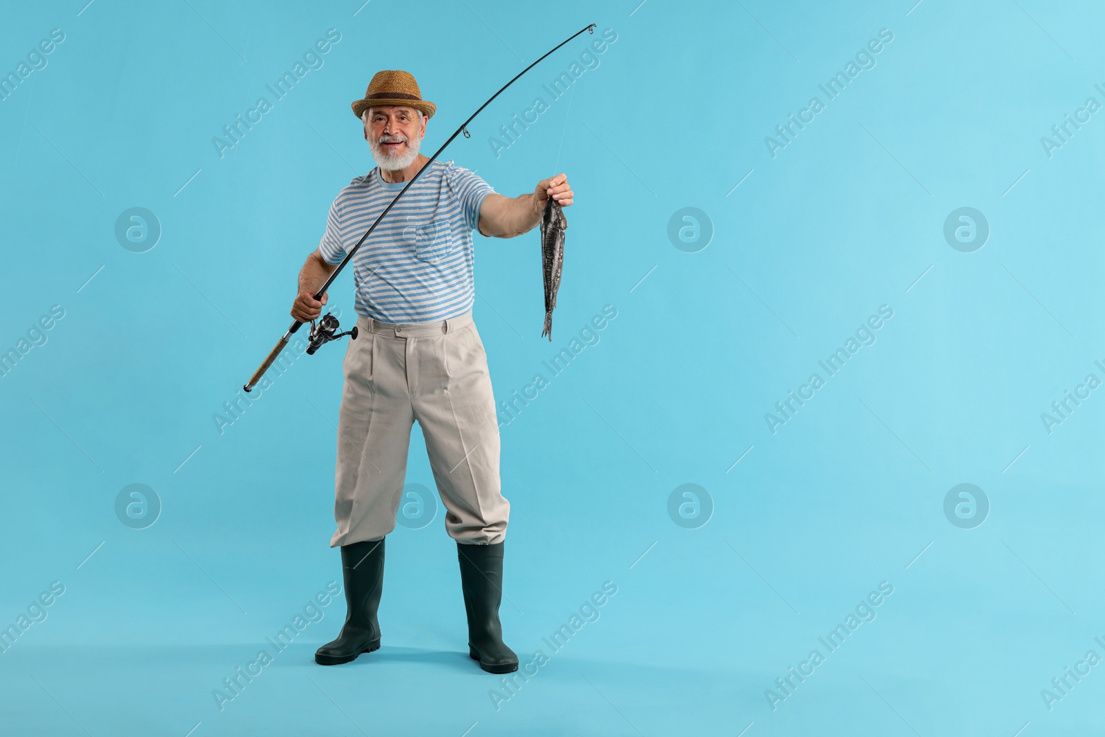 Photo of Fisherman with rod and catch on light blue background