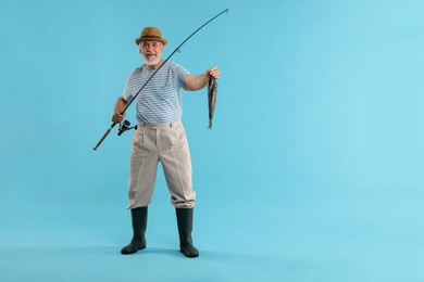 Photo of Fisherman with rod and catch on light blue background