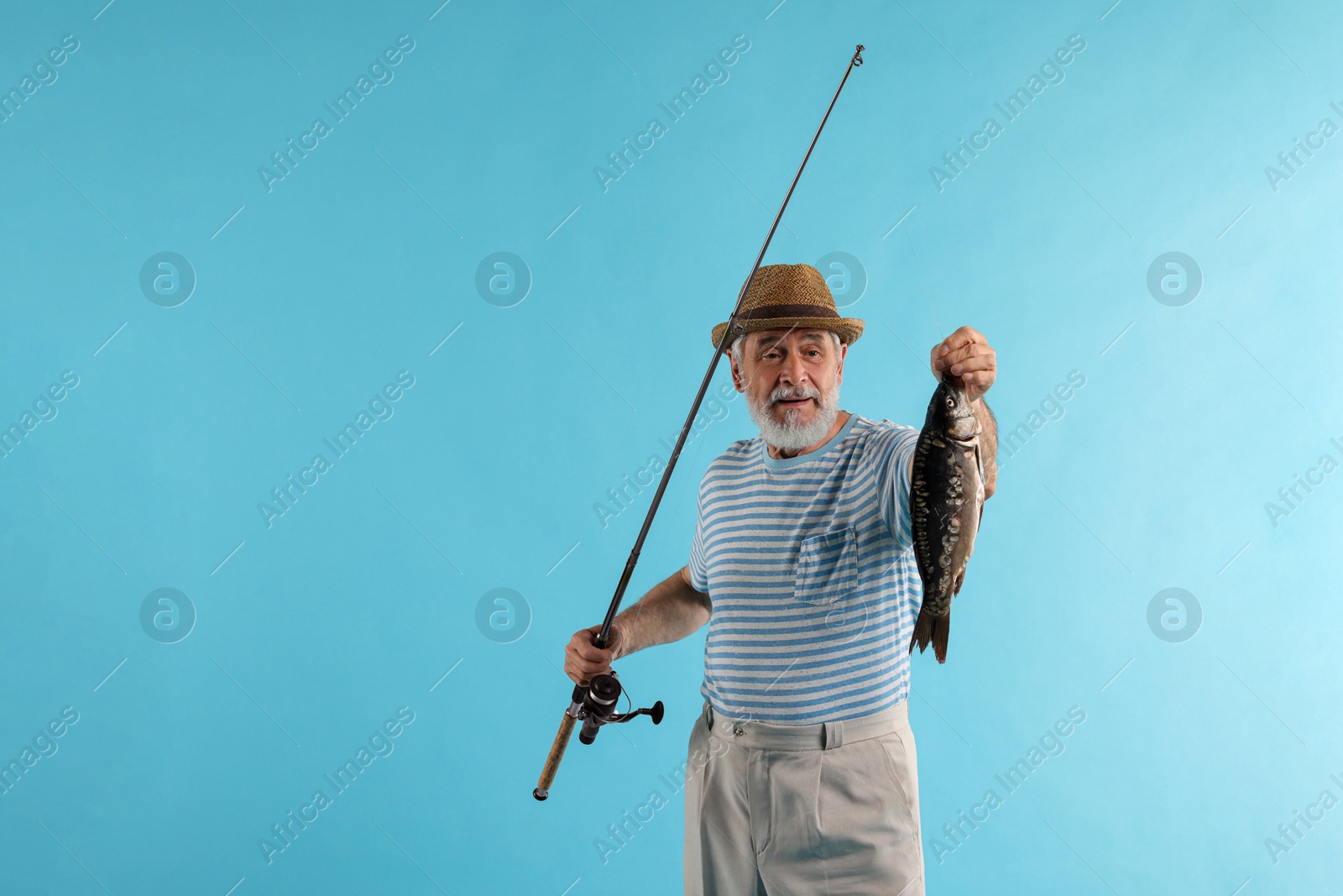 Photo of Fisherman with rod and catch on light blue background