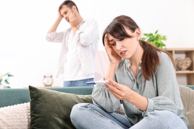 Photo of Worried young couple with pregnancy test at home