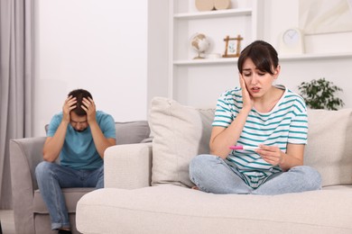 Photo of Worried young couple with pregnancy test at home