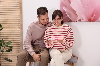 Photo of Happy young couple with pregnancy test at home