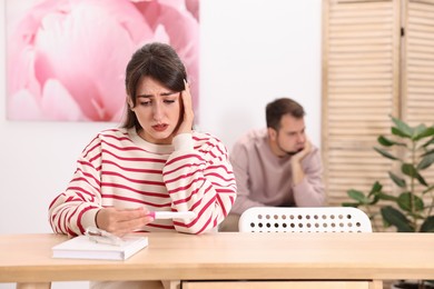 Photo of Worried young couple with pregnancy test at home