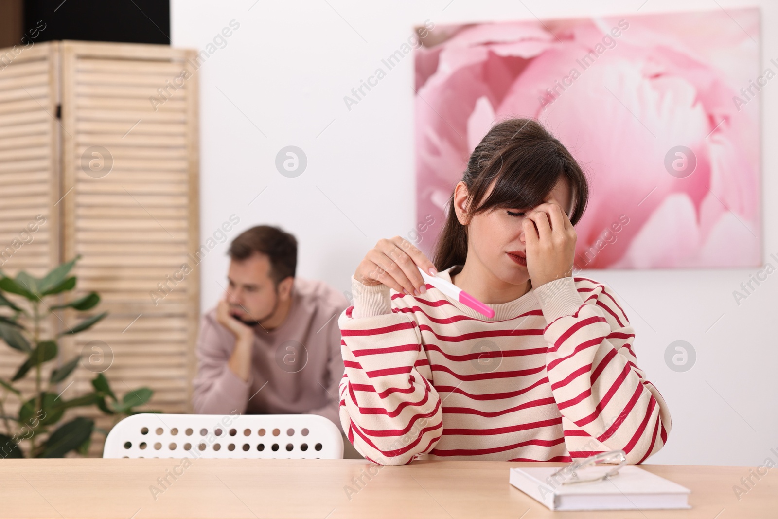 Photo of Worried young couple with pregnancy test at home