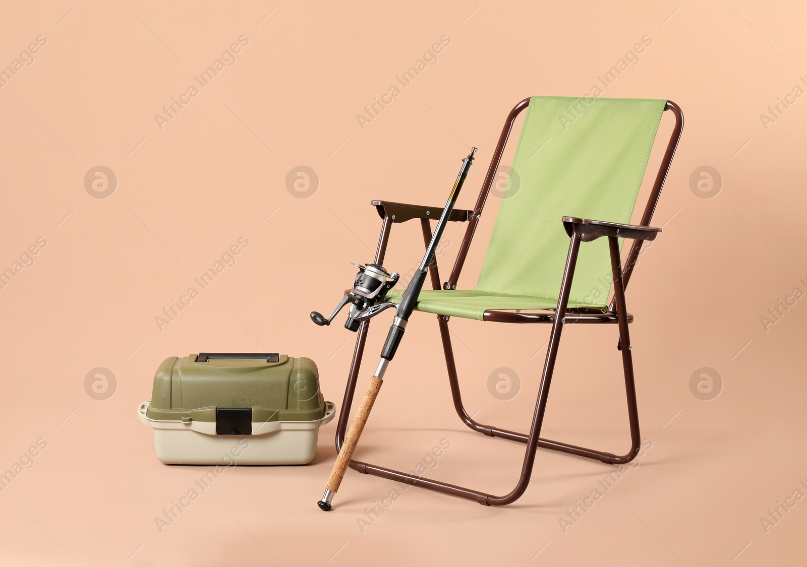 Photo of Folding chair, fishing rod and tackle box on beige background