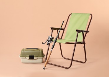 Folding chair, fishing rod and tackle box on beige background