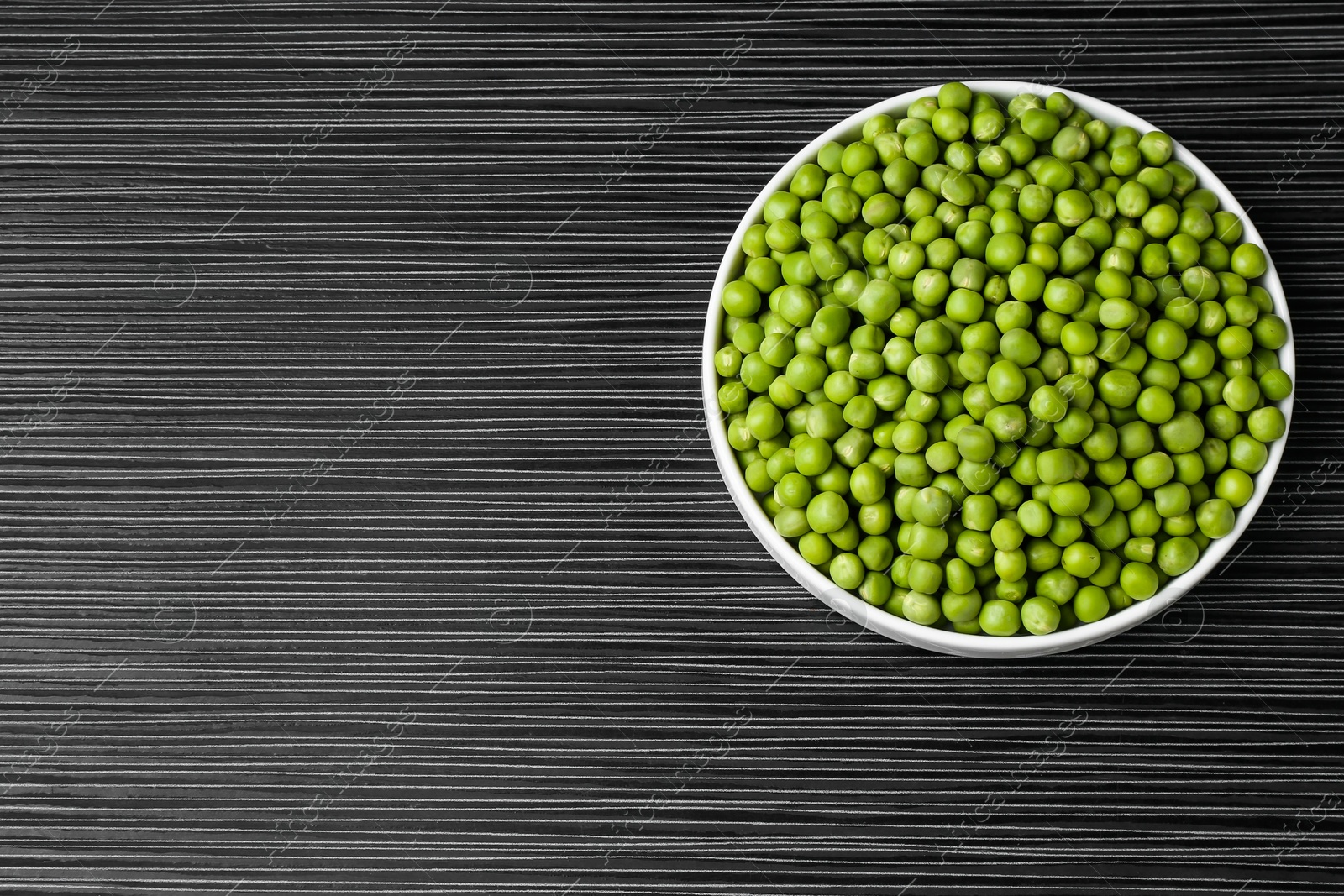 Photo of Fresh green peas on black wooden table, top view. Space for text