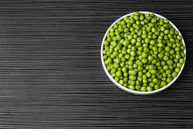 Photo of Fresh green peas on black wooden table, top view. Space for text