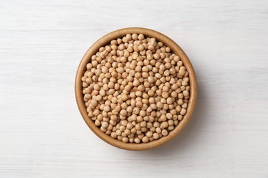 Dried peas in bowl on light wooden table, top view