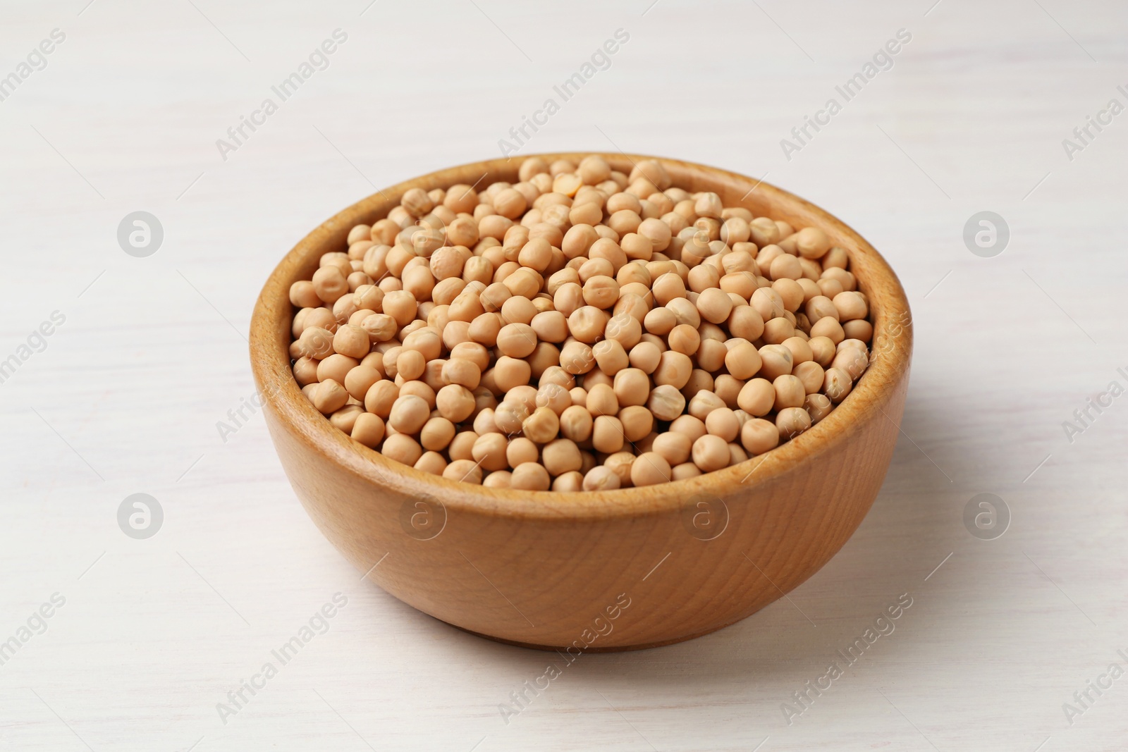 Dried peas in bowl on light wooden table, closeup Photo of Dried peas in bowl on light wooden table, closeup