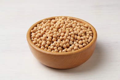 Photo of Dried peas in bowl on light wooden table, closeup