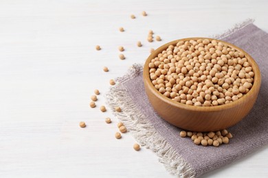 Dried peas in bowl on light wooden table, closeup. Space for text