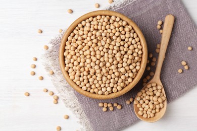 Photo of Dried peas in bowl and spoon on light wooden table, top view