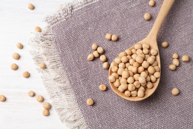 Spoon with dried peas on light wooden table, above view