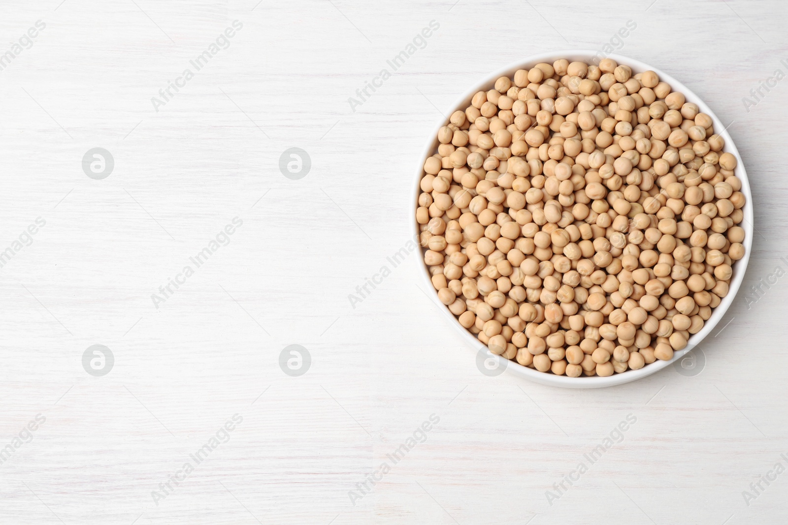 Photo of Dried peas on light wooden table, top view. Space for text