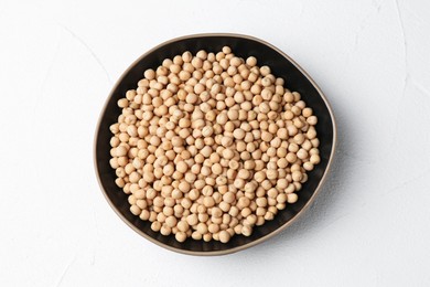 Dried peas in bowl on white textured table, top view