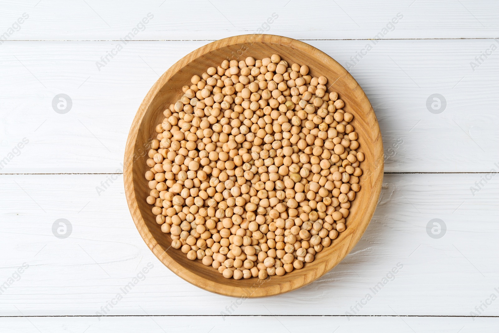 Photo of Dried peas in bowl on white wooden table, top view