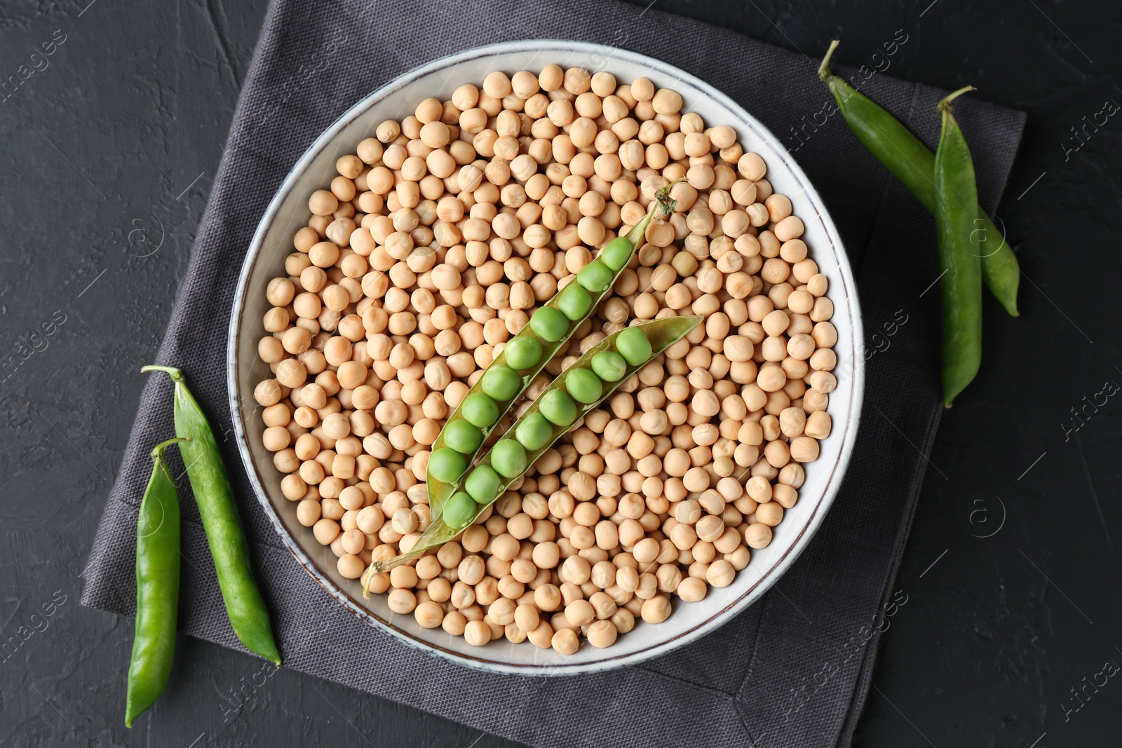 Photo of Dried peas and pods with fresh ones on dark textured table, top view