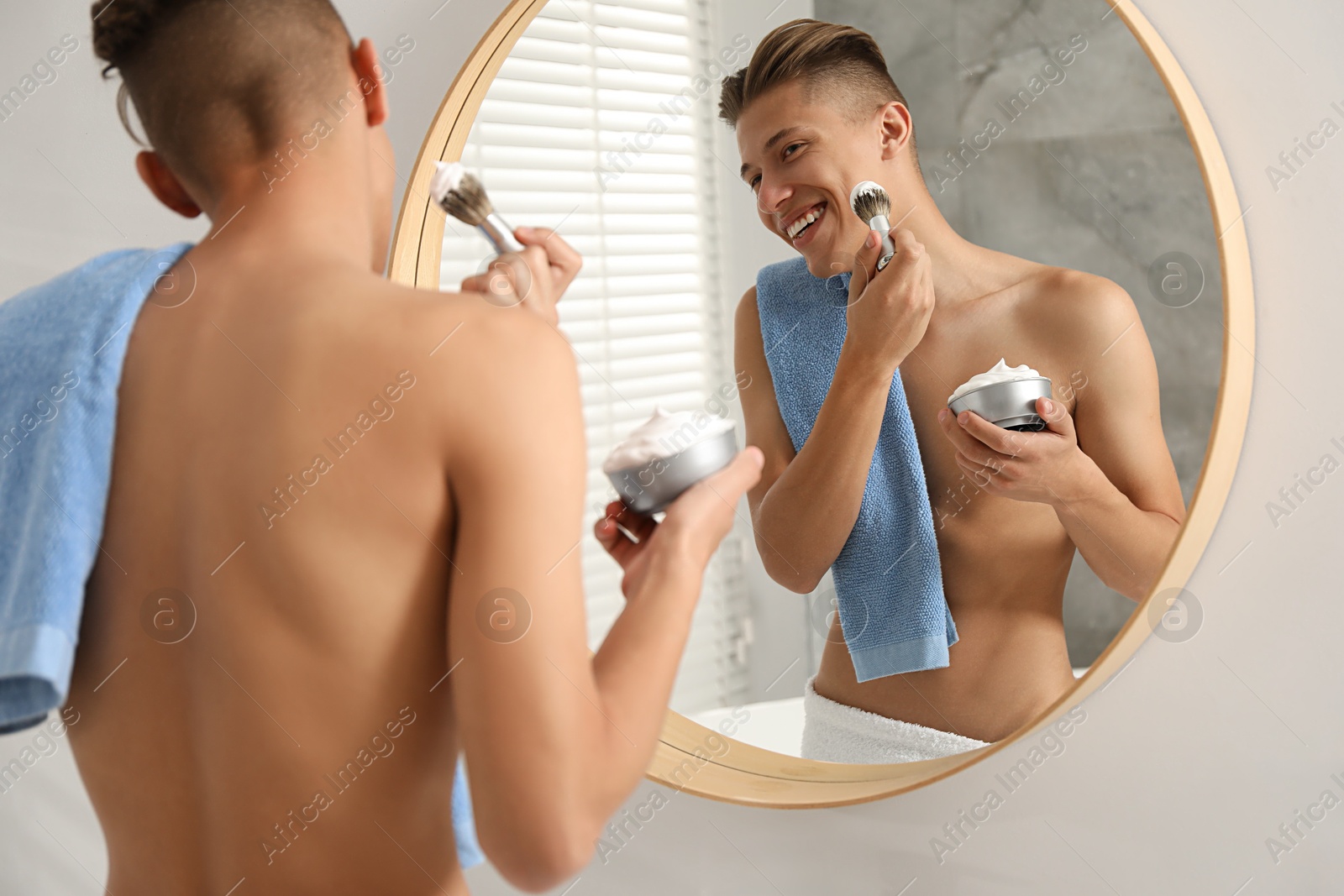 Photo of Handsome man applying shaving foam near mirror in bathroom