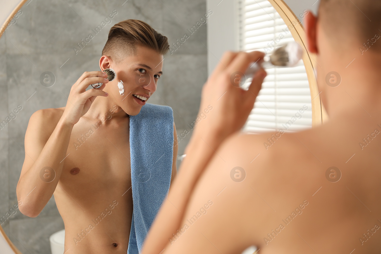 Photo of Handsome man applying shaving foam near mirror in bathroom