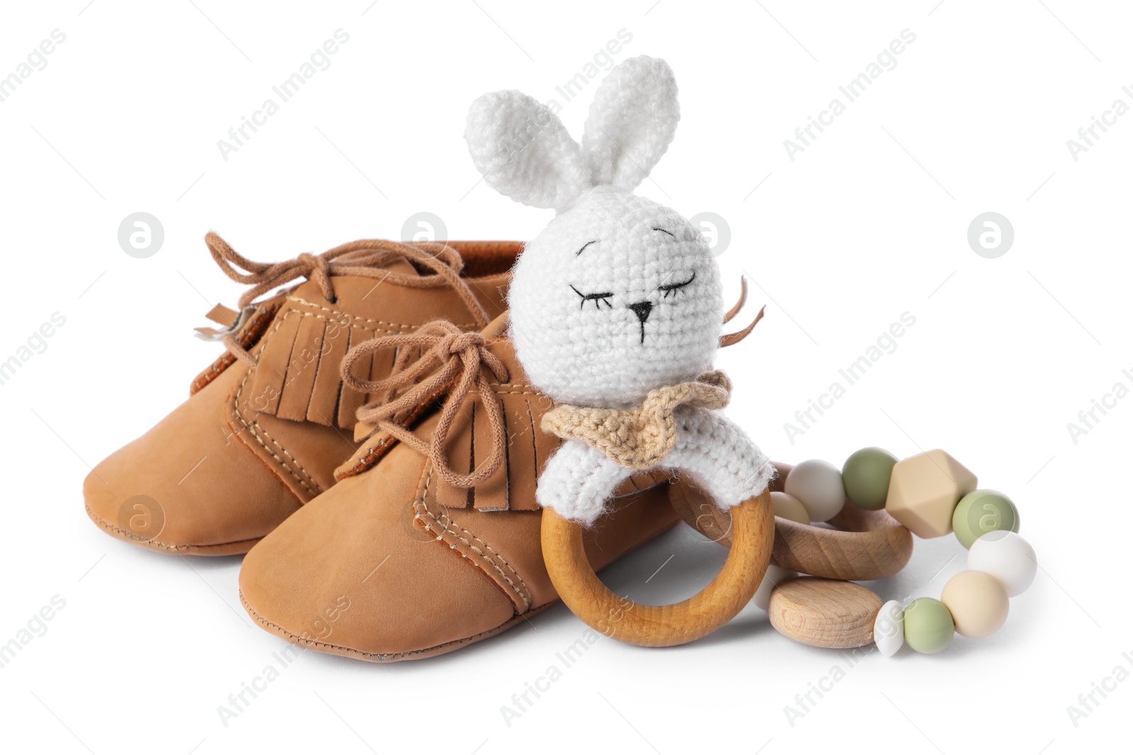 Photo of Wooden rattles and baby shoes isolated on white