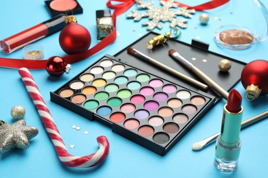 Photo of Different decorative cosmetic products and Christmas decor on light blue background