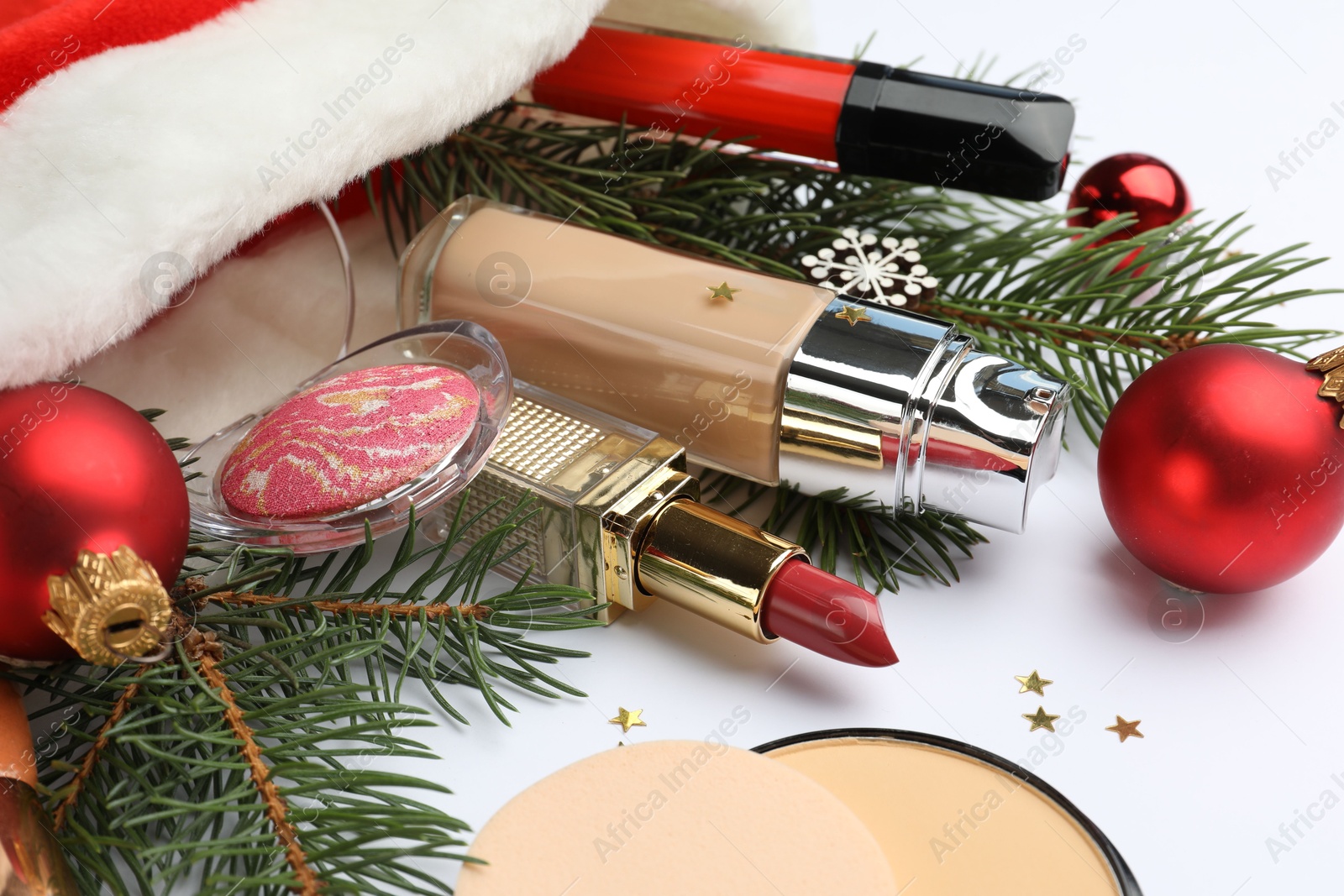 Photo of Santa hat with different decorative cosmetics and Christmas decor on white background, closeup