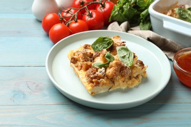 Tasty baked cauliflower, basil, tomatoes and sauce on light blue wooden table