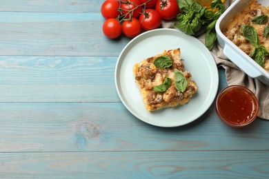 Photo of Tasty baked cauliflower, basil, tomatoes and sauce on light blue wooden table, top view. Space for text