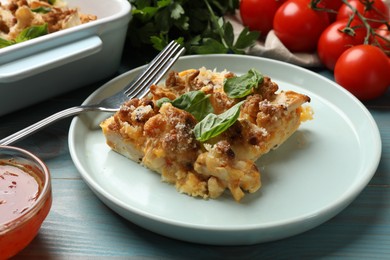 Tasty baked cauliflower, basil, sauce and tomatoes on light blue wooden table, closeup