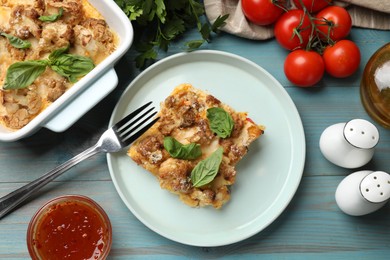 Photo of Tasty baked cauliflower, basil, spices, sauce and tomatoes on light blue wooden table, top view