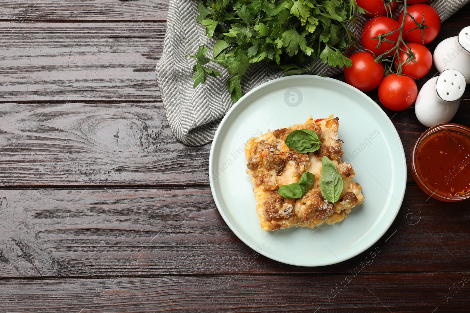 Photo of Tasty baked cauliflower, basil, spices, sauce and tomatoes on wooden table, top view. Space for text