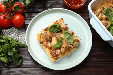 Photo of Tasty baked cauliflower, basil, parsley and tomatoes on wooden table, top view