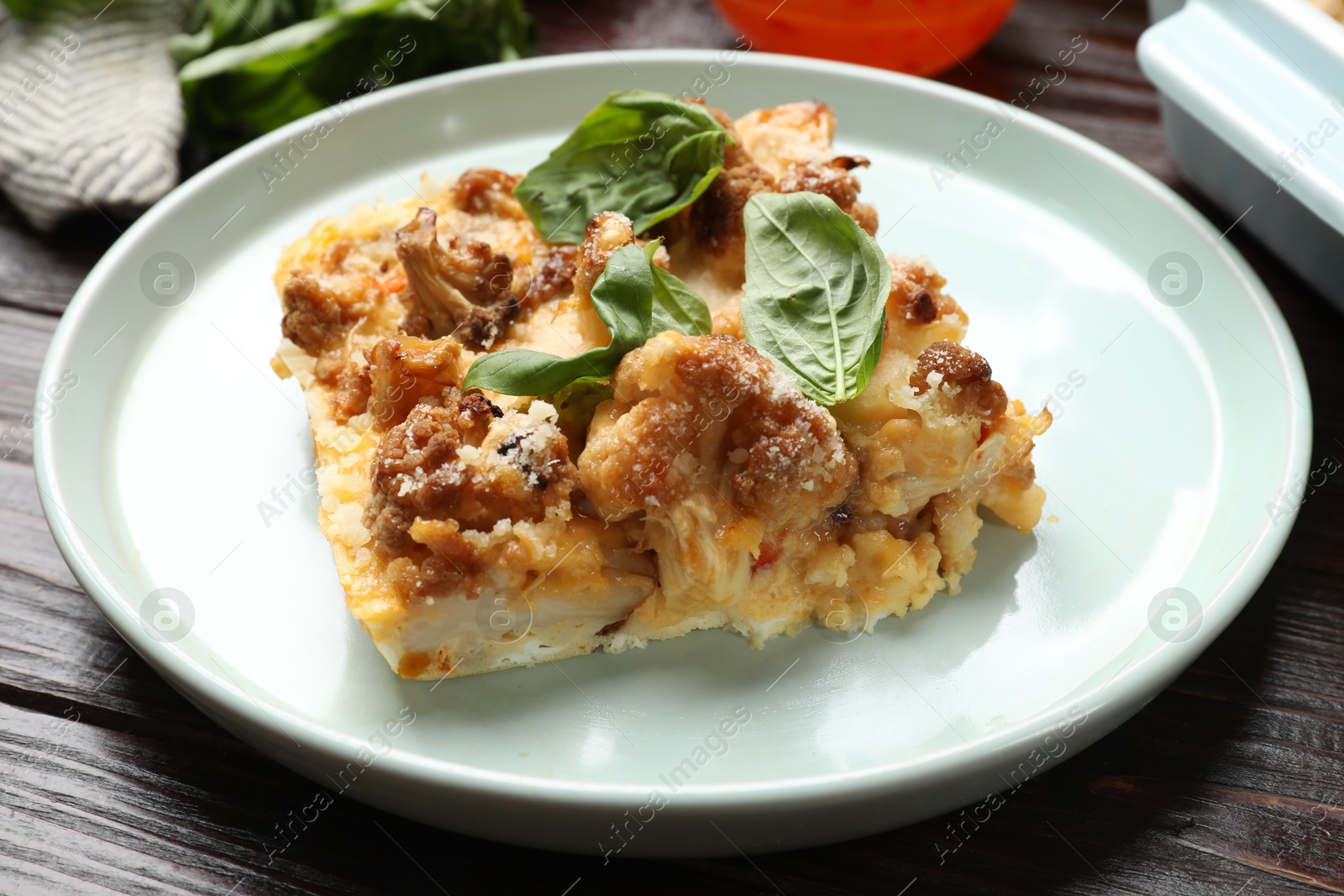 Photo of Tasty baked cauliflower and basil on wooden table, closeup