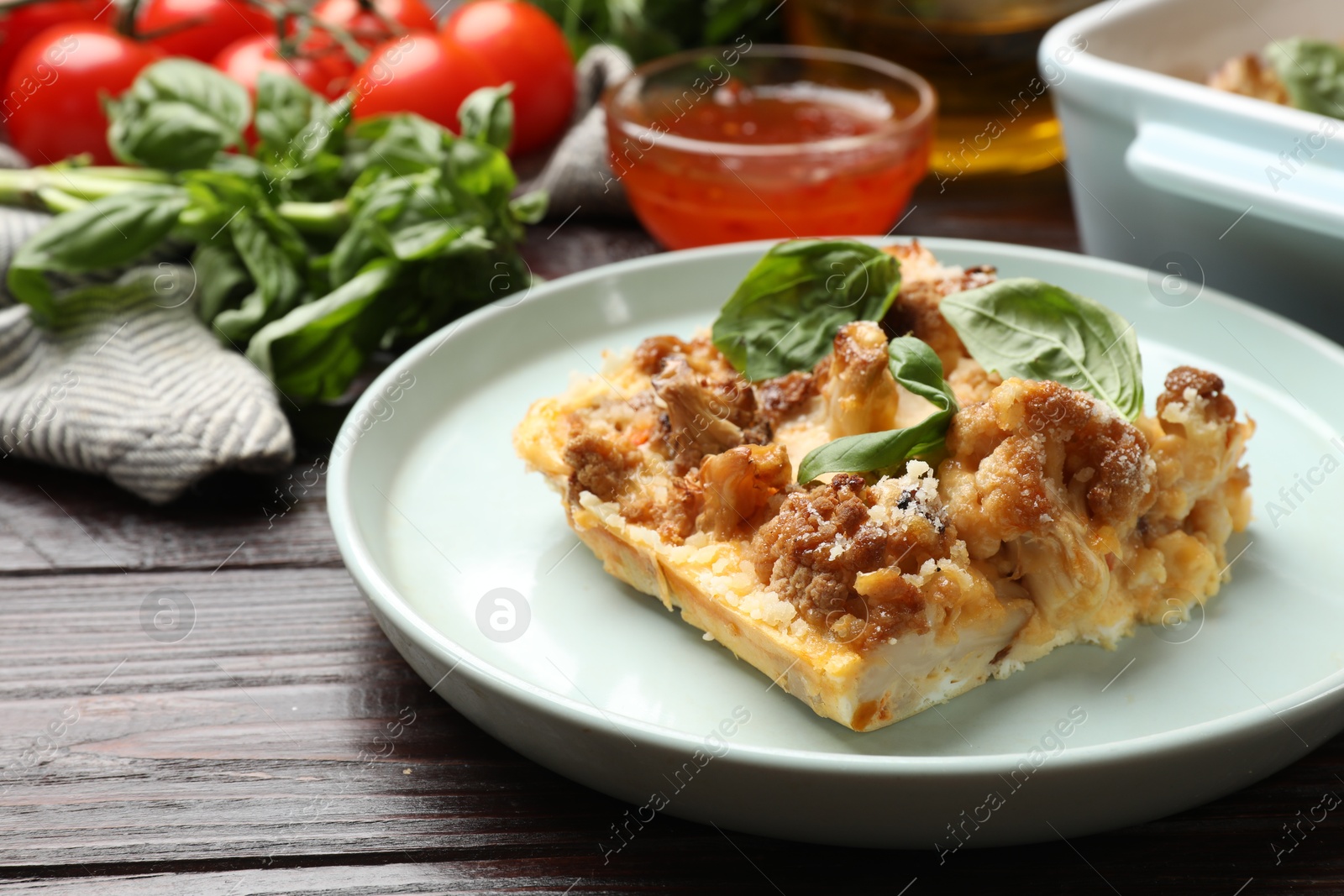 Photo of Tasty baked cauliflower and basil on wooden table, closeup