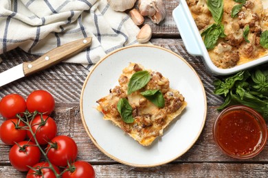 Photo of Tasty baked cauliflower, basil, tomatoes, garlic and sauce on wooden table, top view