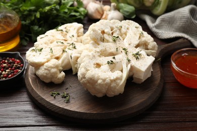 Photo of Uncooked cauliflower steaks and products on wooden table, closeup