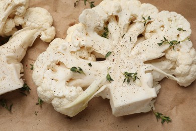 Photo of Uncooked cauliflower steaks with spices on parchment paper, closeup