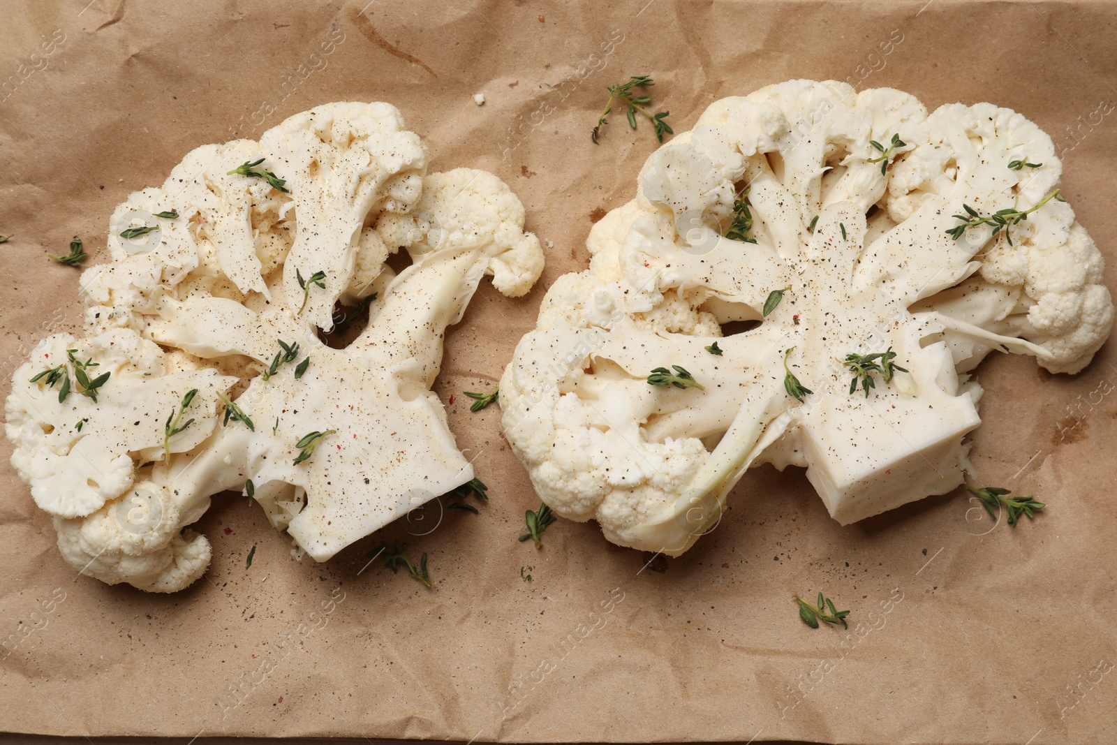 Photo of Uncooked cauliflower steaks with spices on parchment paper, flat lay