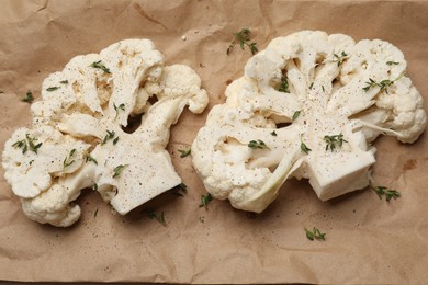 Photo of Uncooked cauliflower steaks with spices on parchment paper, flat lay